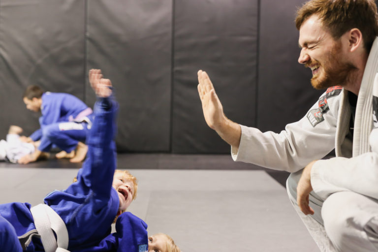 Van Isle BJJ coach high-fiving a happy child during kids class